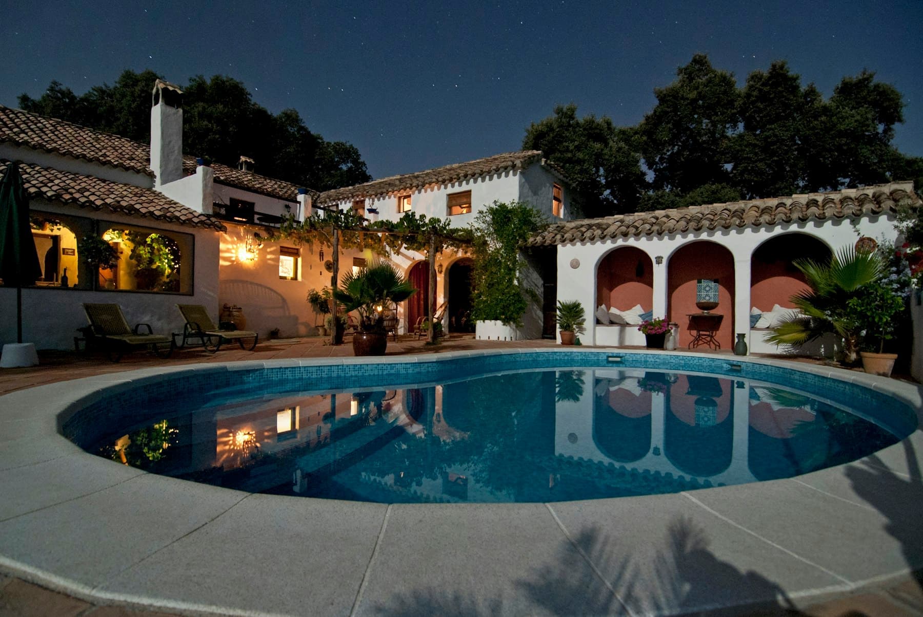 Independent house lit at dusk with landscaped garden and pool