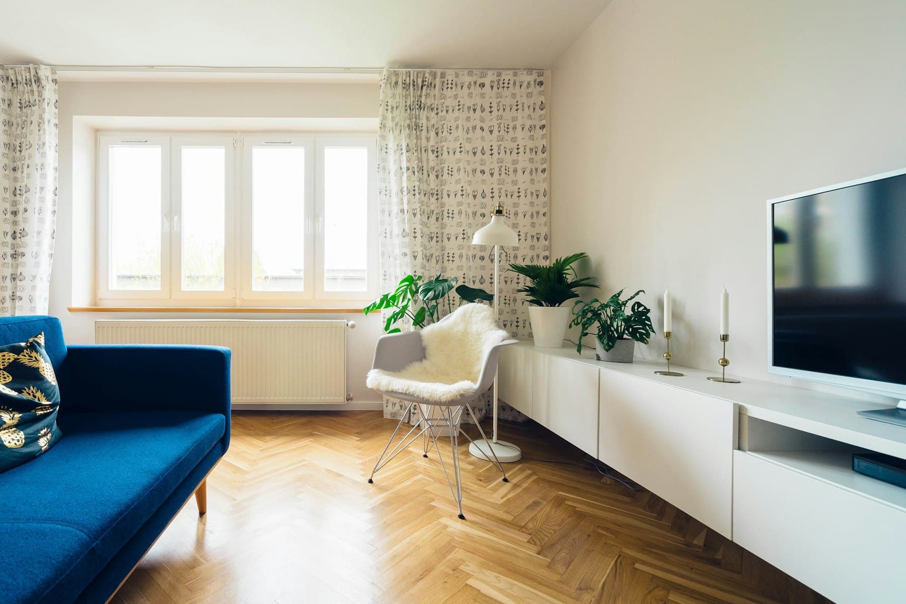 Living room with blue sofa, television unit and garden-facing windows